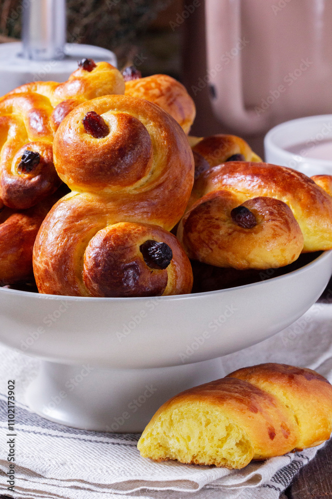 Traditional saffron Swedish buns lussekatt in different shapes, served with cocoa on a wooden table. Buns for St. Lucia's Day.