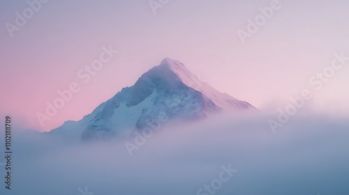 Majestic mountain peak illuminated by the soft glow of sunrise above a sea of clouds