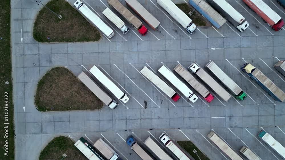Drone shot of truck parking in Europe seen from above. Aerial footage of rows of vehicles parked for rest at a service station. Neatly placed trucks arranged at a truck stop seen from a helicopter.

