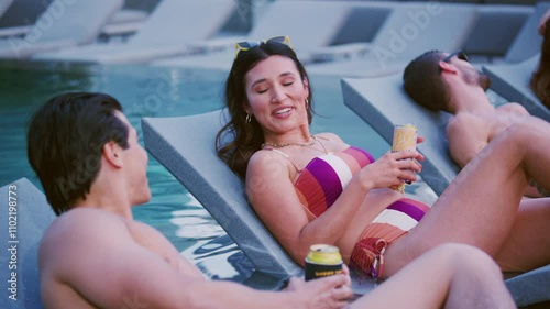 Two people chat while lounging in pool chairs in the sun