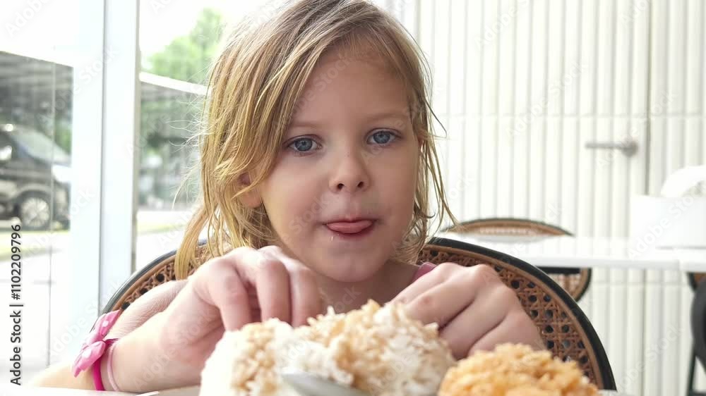 A joyful little girl is happily eating fried chicken 