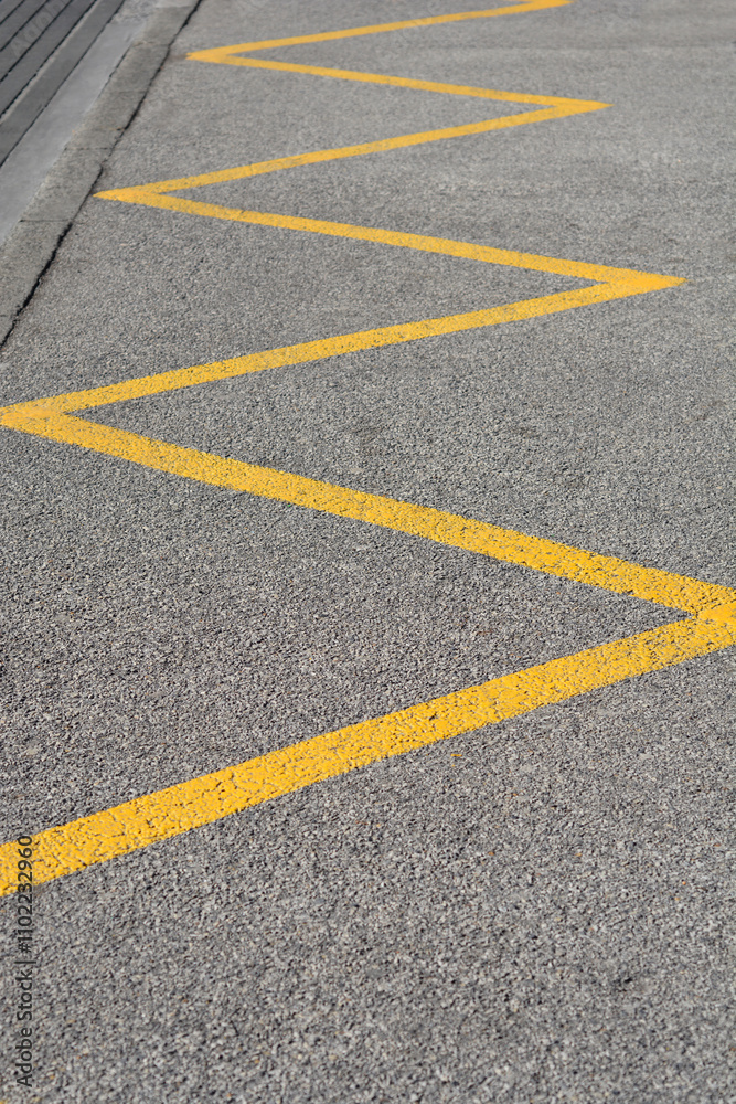 Yellow zig-zag line on the road signaling a no-stopping and no-parking zone to drivers Yellow zig-zag line on the road signaling a no-stopping and no-parking zone to drivers