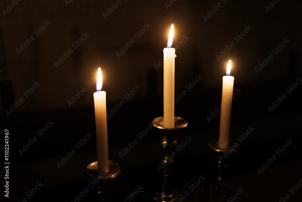 Three glowing candles burning in the dark, creating a serene and tranquil atmosphere Three glowing candles burning in the dark, creating a serene and tranquil atmosphere