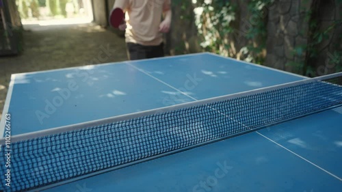 A man shows ping pong skills at a blue table, highlighting competition