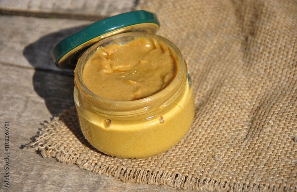 open glass jar with mustard on the table open glass jar with mustard on the table