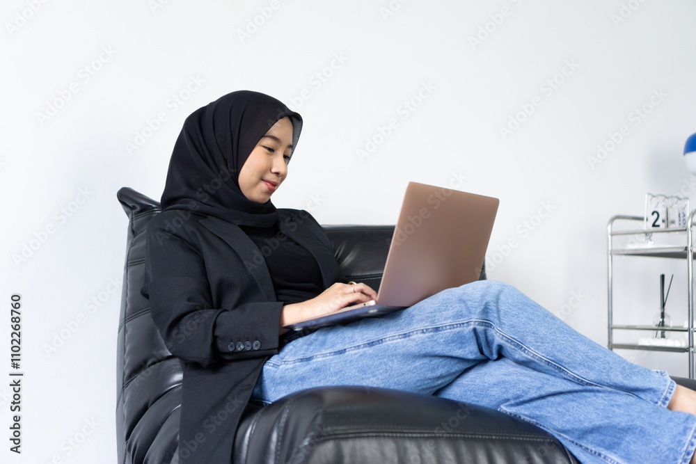 asian muslim women with hijab doing online remote work using laptop while showing smile and happy face expression