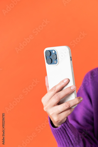 Modern smartphone in female hand against orange background