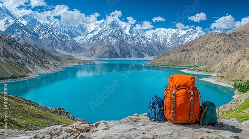 a bag pack set on a mountain ridge and lake Saif ul Maloo is visibal in the background some of the traveling equipment is set with the bagpack photo