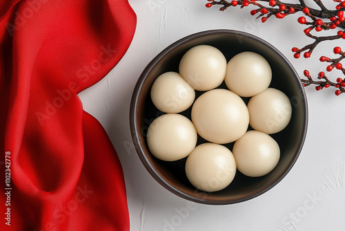 chinese new year feast, traditional bowl holding silk-wrapped tangyuan, wooden chopsticks, red couplets, and harmonious decor creates a delightful arrangement photo