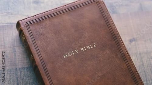 Still Close-Up Shot of Holy Bible opening to the Book of Genesis on top of wooden table soft lighting by the window and color graded
