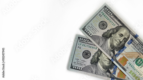 Close-up of two 100 US dollar bills angled on a white background, providing ample copy space. Ideal for use in financial advertisements, banking promotions, or educational content about currency and f photo