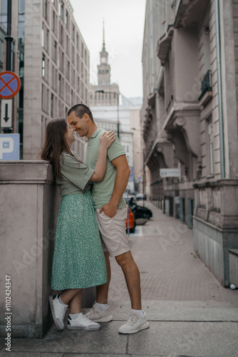 Happy couple of tourists walking embraced while sightseeing the town. Happy couple in front of palace of culture and science in Warsaw, Poland. Close up of a couple kissing.
