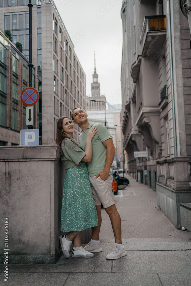 Naklejka premium Happy couple of tourists walking embraced while sightseeing the town. Happy couple in front of palace of culture and science in Warsaw, Poland. Close up of a couple kissing.
