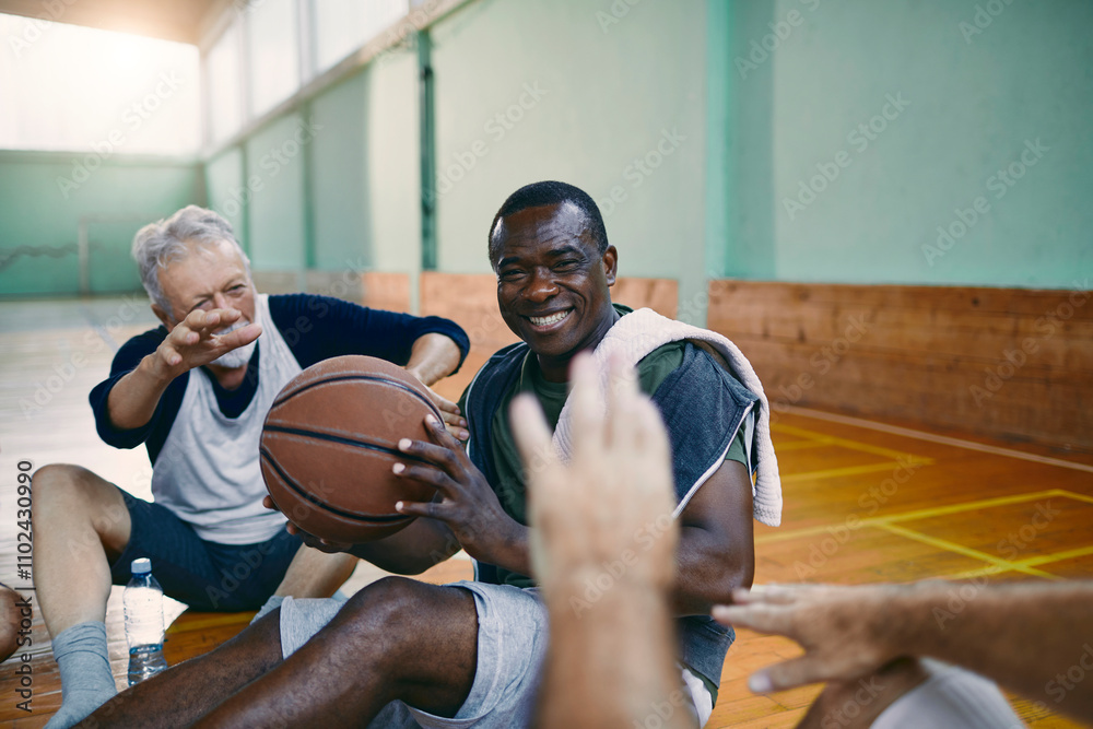 Senior men taking a break from playing basketball in an indoor gym Senior men taking a break from playing basketball in an indoor gym
