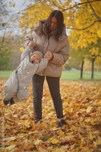 Little boy playing in autumn park. Child on yellow fallen leaves on a sunny autumn day.