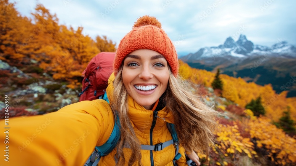 young woman dressed in a bright orange hat and yellow jacket smiles widely while taking a selfie during her autumn hike in the mountains, surrounded by beautiful fall colors young woman dressed in a bright orange hat and yellow jacket smiles widely while taking a selfie during her autumn hike in the mountains, surrounded by beautiful fall colors