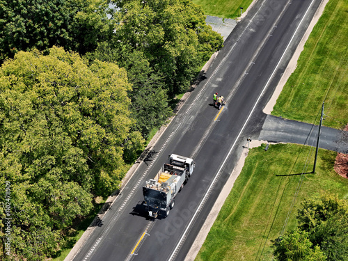 county road department restriping newly blacktoped road photo