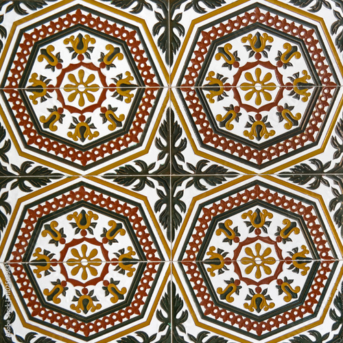 Fragment of building wall with glazed ceramic tiles, embossed vintage Mudejar, close up. Traditional ornate Spanish architecture. Abstract background, textured ornate pattern for design or backdrop.
