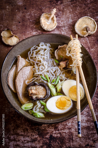 Ramen noodles with chopsticks surrounded by mushrooms photo