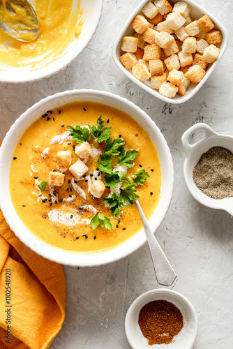 Delicious pumpkin soup in a bowl with cream sauce and croutons. Top view.