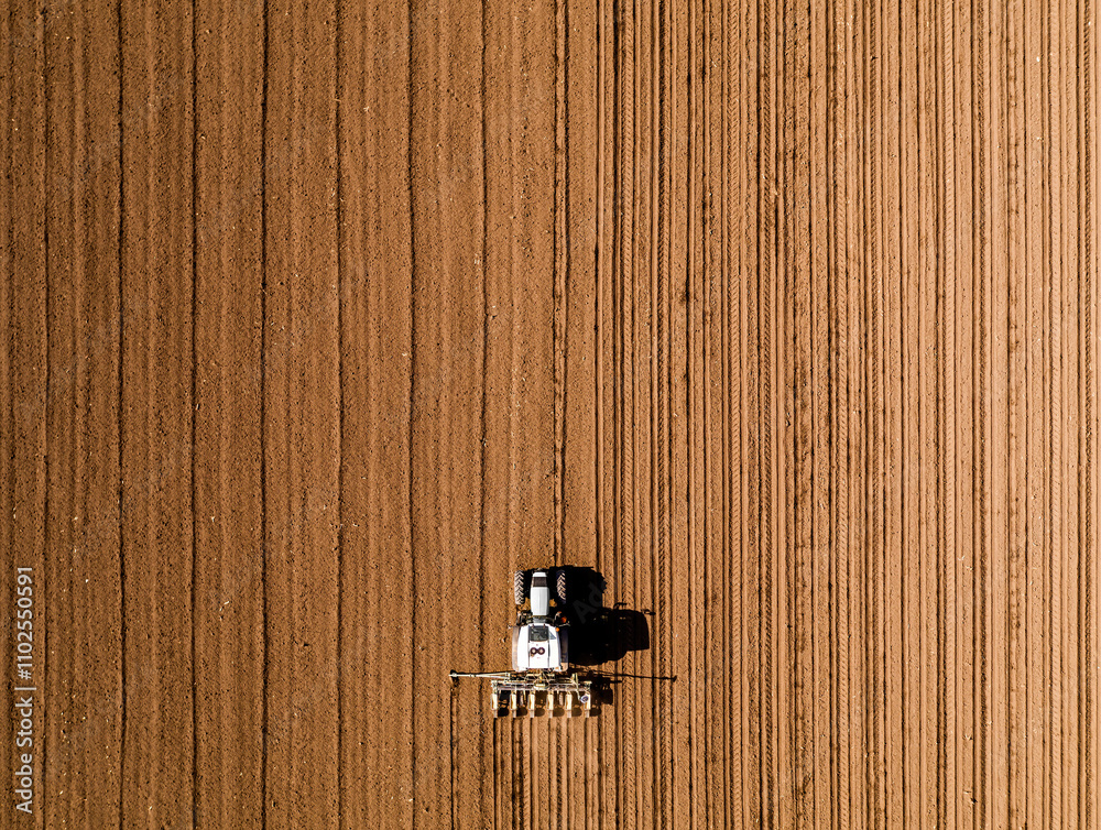 Tractor seeding crops in plowed field aerial view Tractor seeding crops in plowed field aerial view
