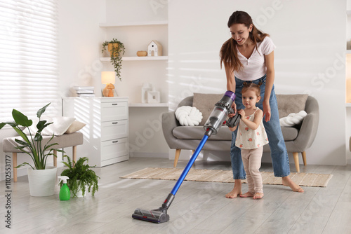 Εκτύπωση καμβά Smiling young woman and her daughter cleaning floor with cordless vacuum cleaner