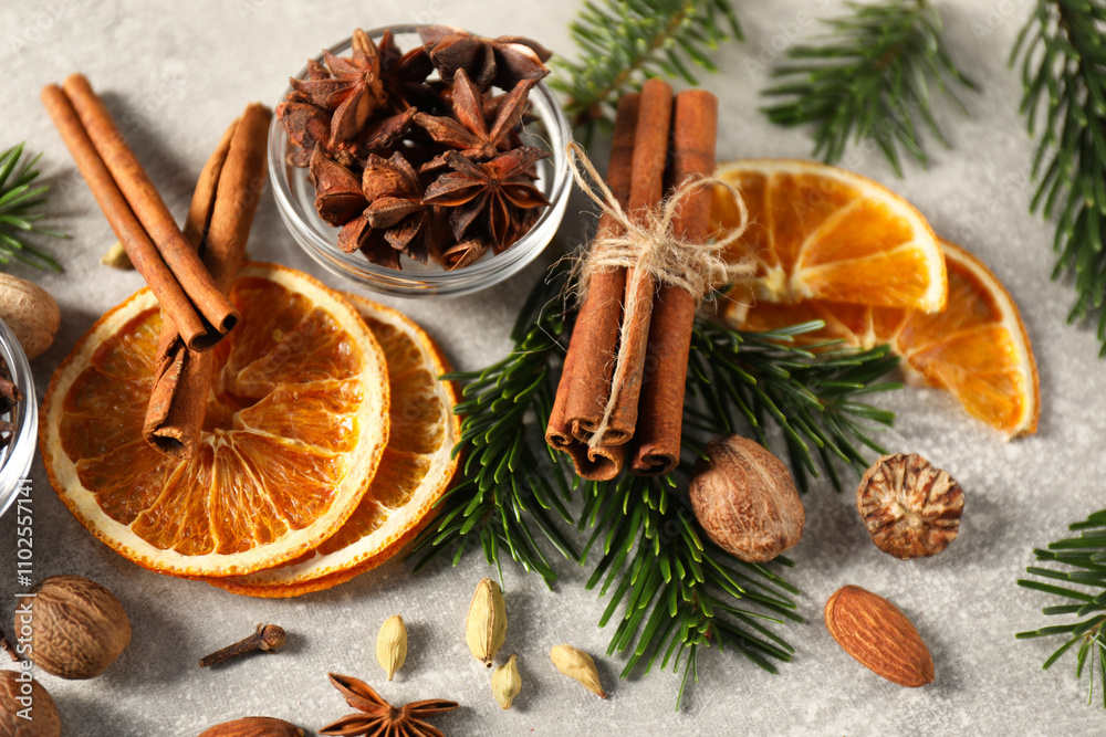 Different spices, dried orange slices and fir tree branches on light grey table, closeup. Christmas season Different spices, dried orange slices and fir tree branches on light grey table, closeup. Christmas season