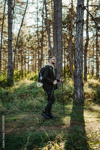 Young caucasian man hiking or trekking through the forest 