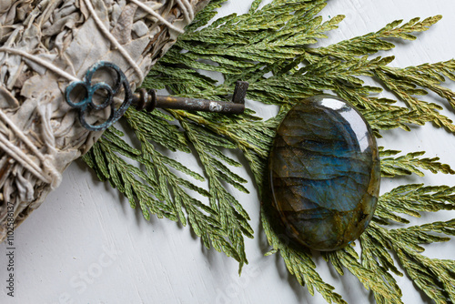 A top view image of a labradorite crystal on a cedar bow with a white sage smudge stick.