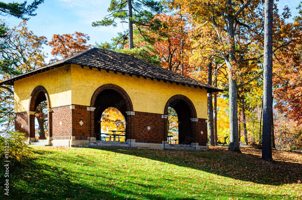 Obraz premium Empty park pavilion in the morning sunlight among fall leaves.