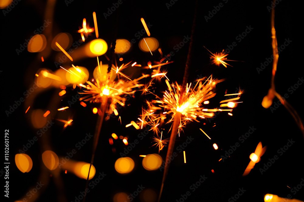 Obraz premium Sparkling shining fireworks with gold glitter and bokeh on black background.Sparkler Fireworks with Bokeh Effect.Close-Up of Sparklers Against Dark Background.Sparklers with Bokeh Lights at Night