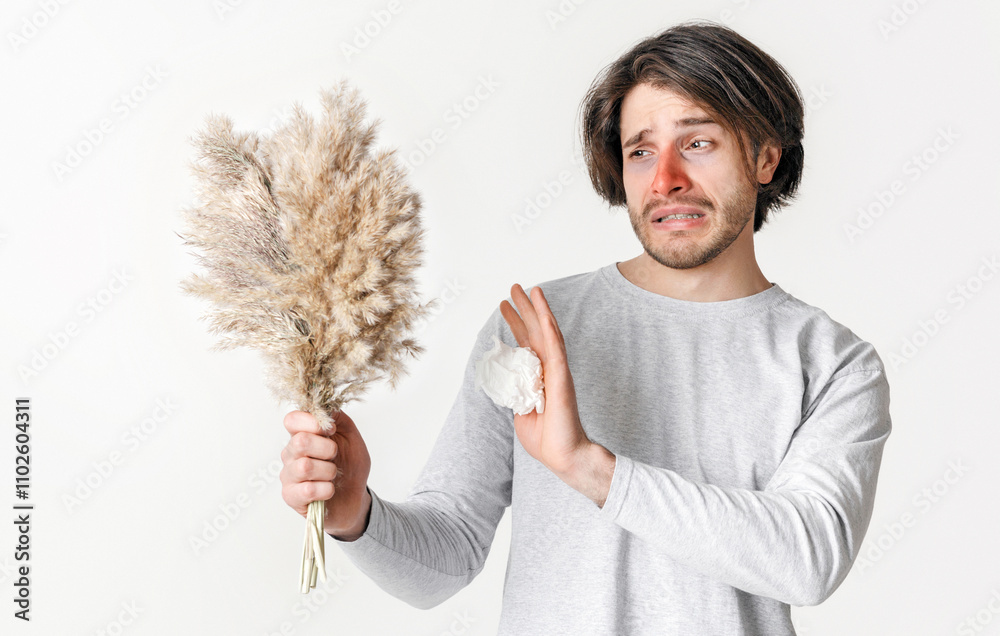Symptoms of pollen allergy. Suffering man with red nose and napkin refuses plants, isolated on light background, studio shot Symptoms of pollen allergy. Suffering man with red nose and napkin refuses plants, isolated on light background, studio shot