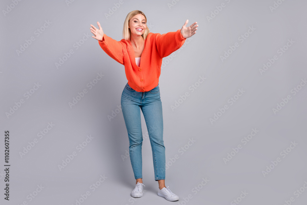 Portrait of nice young girl arms welcome you orange cardigan isolated on grey color background Portrait of nice young girl arms welcome you orange cardigan isolated on grey color background