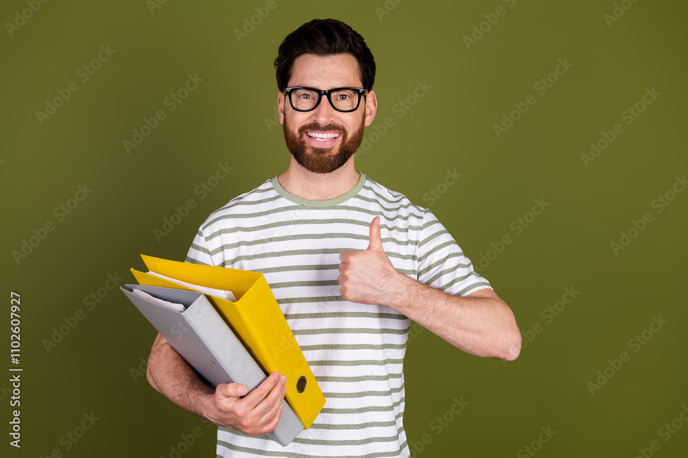 Photo of satisfied attractive man wear stylish clothes hold folders thumb up isolated on khaki color background Photo of satisfied attractive man wear stylish clothes hold folders thumb up isolated on khaki color background