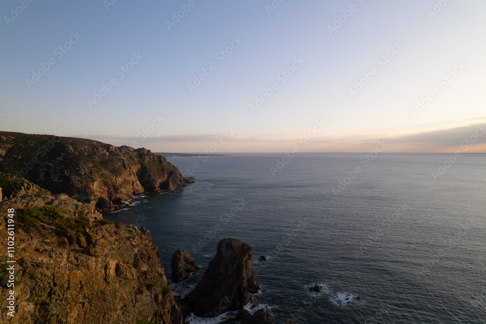 Scenic coastal view during sunset at a rocky shoreline with gentle waves Scenic coastal view during sunset at a rocky shoreline with gentle waves