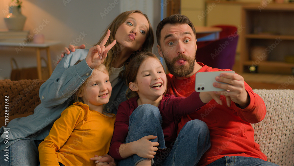 Caucasian happy family mother father kids little girls daughters posing grimace photo on mobile phone at evening home funny parents children record video online blog smartphone selfie social media app
