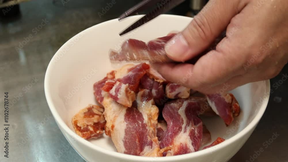 The raw pork is cut with kitchen scissors and mixed with black pepper before cooking. The raw pork is cut with kitchen scissors and mixed with black pepper before cooking.
