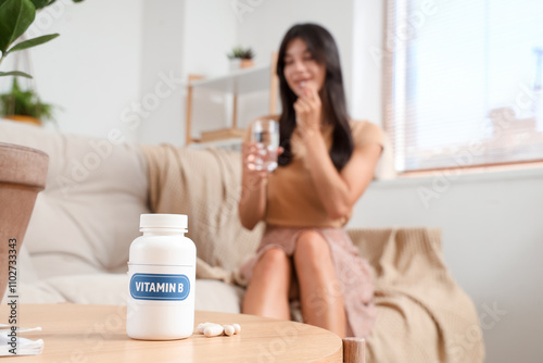 Young woman taking pills at...