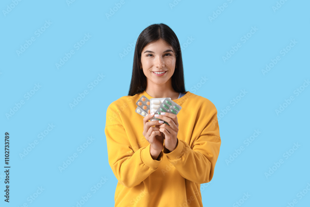 Young woman with different vitamin B pills on blue background Young woman with different vitamin B pills on blue background