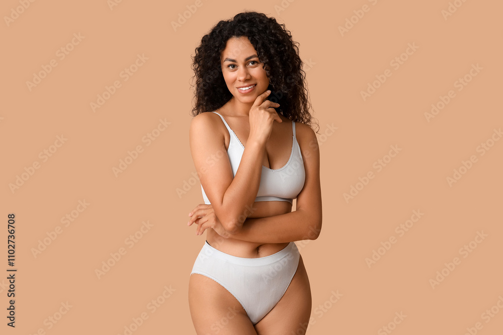 Beautiful young happy African-American body positive woman in underwear on beige background Beautiful young happy African-American body positive woman in underwear on beige background