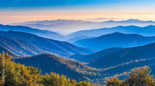 Majestic mountain range at sunrise with layered blue hues and colorful foliage