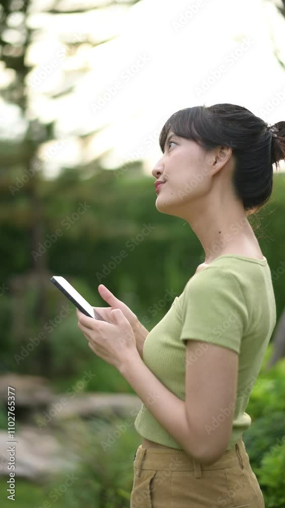 Vertical video of Smiling Woman Using Smartphone Outdoors in Greenery Vertical video of Smiling Woman Using Smartphone Outdoors in Greenery