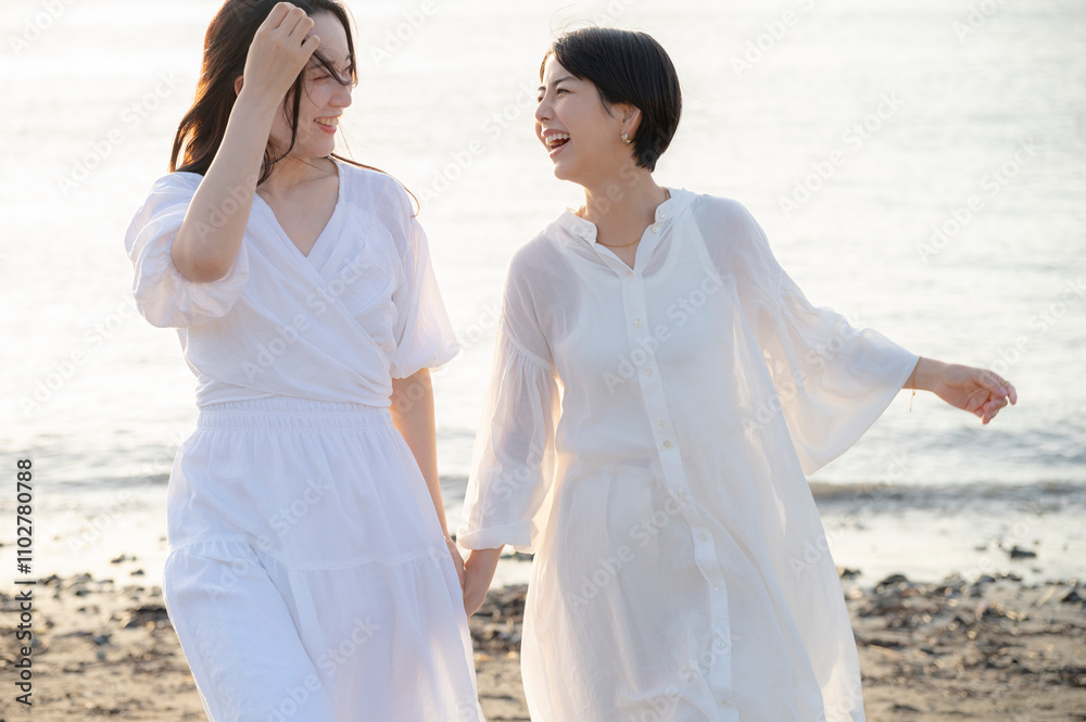 Two Women Laughing Together on the Beach at Sunset Two Women Laughing Together on the Beach at Sunset