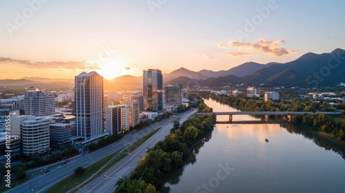 Aerial View of City Skyline at Sunset with Mountains in the Background and River Reflecting Warm Hues of Evening Light, Scenic Urban Landscape