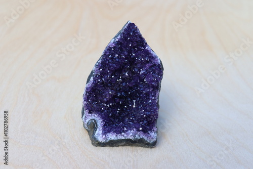 A geode of amethyst on a wood background. Geology and gemstone. Collection of stone and amethyst druse with a dark purple color. Mineral and benefits. Stone of the month of February.