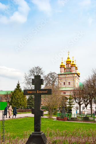 Christ is Risen. The inscription on the grave cross in the Trinity-Sergius Lavra against the background of the gate church of the Nativity of John the Baptist. Sergiev Posad city