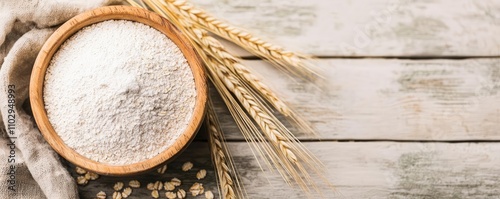 Flour in a wooden bowl with wheat on a rustic wooden background. photo