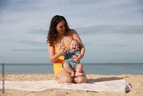 Loving mother spending summer day with her baby son at the beach