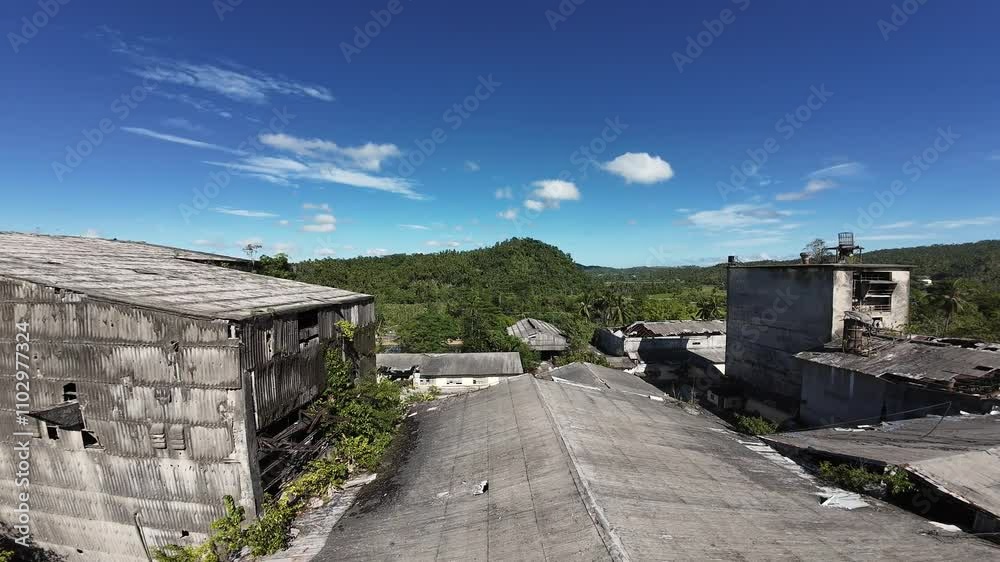 Abandoned cement plant overgrown with trees and vegetation under a bright blue sky in Surigao City Abandoned cement plant overgrown with trees and vegetation under a bright blue sky in Surigao City