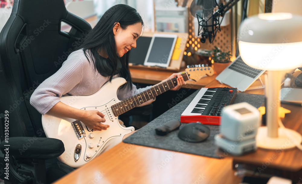 Young asian woman composer playing guitar music with digital technology at home studio Young asian woman composer playing guitar music with digital technology at home studio